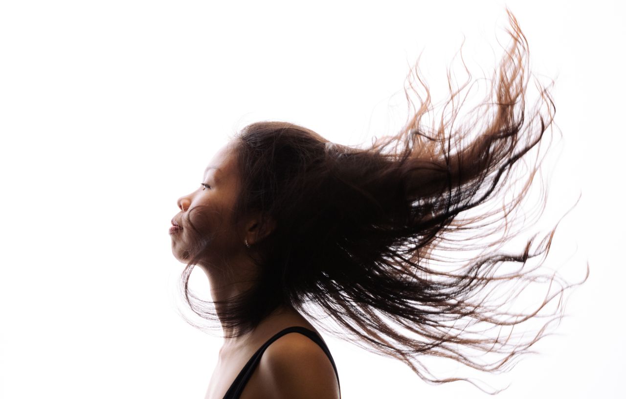 A high-contrast profile of a woman with her hair flowing, showcasing movement and expression.