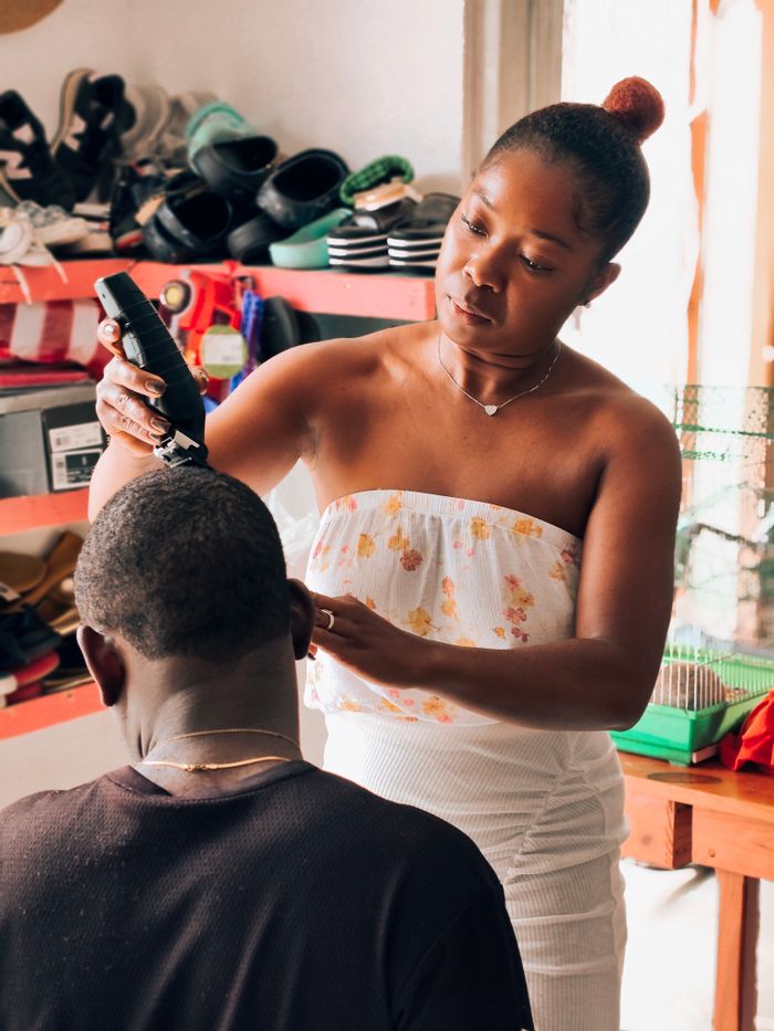 A woman cutting a man's hair indoors, focusing on detailed grooming in a cozy environment.
